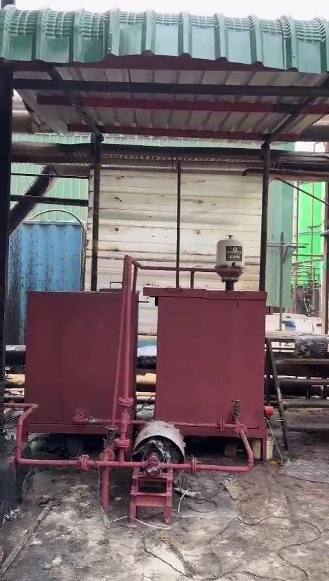 Red thermic oil tanks with a centrifuge filter mounted on one tank and connecting pipework in an industrial plant